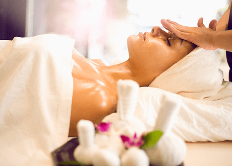 Terapeuta realizando un tratamiento facial holístico a un cliente relajado en un centro de bienestar.